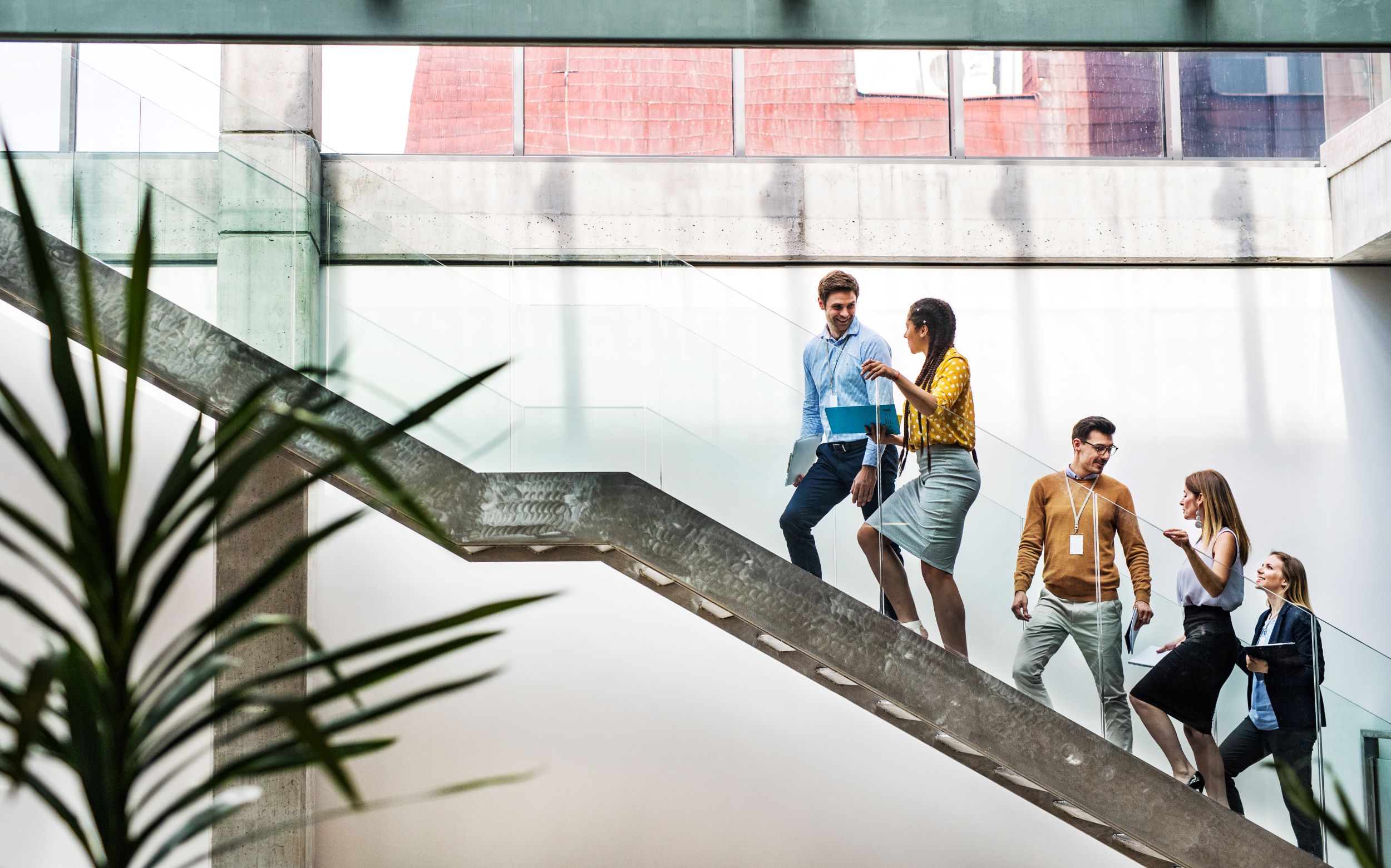 A team ascends a flight of stairs in an office environment