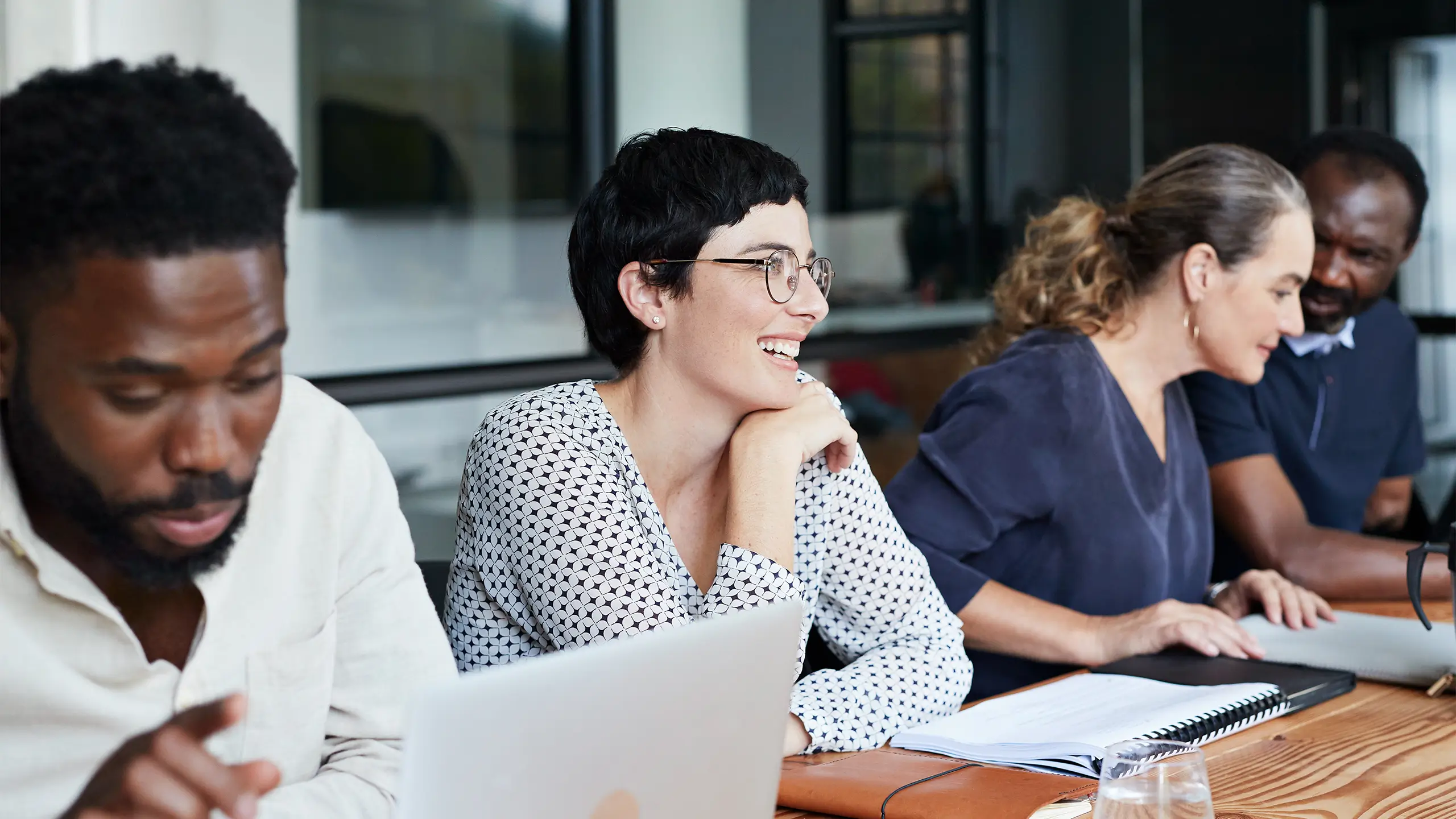 Smiling businesswoman walking in office while male and female coworkers sitting at bright workplace