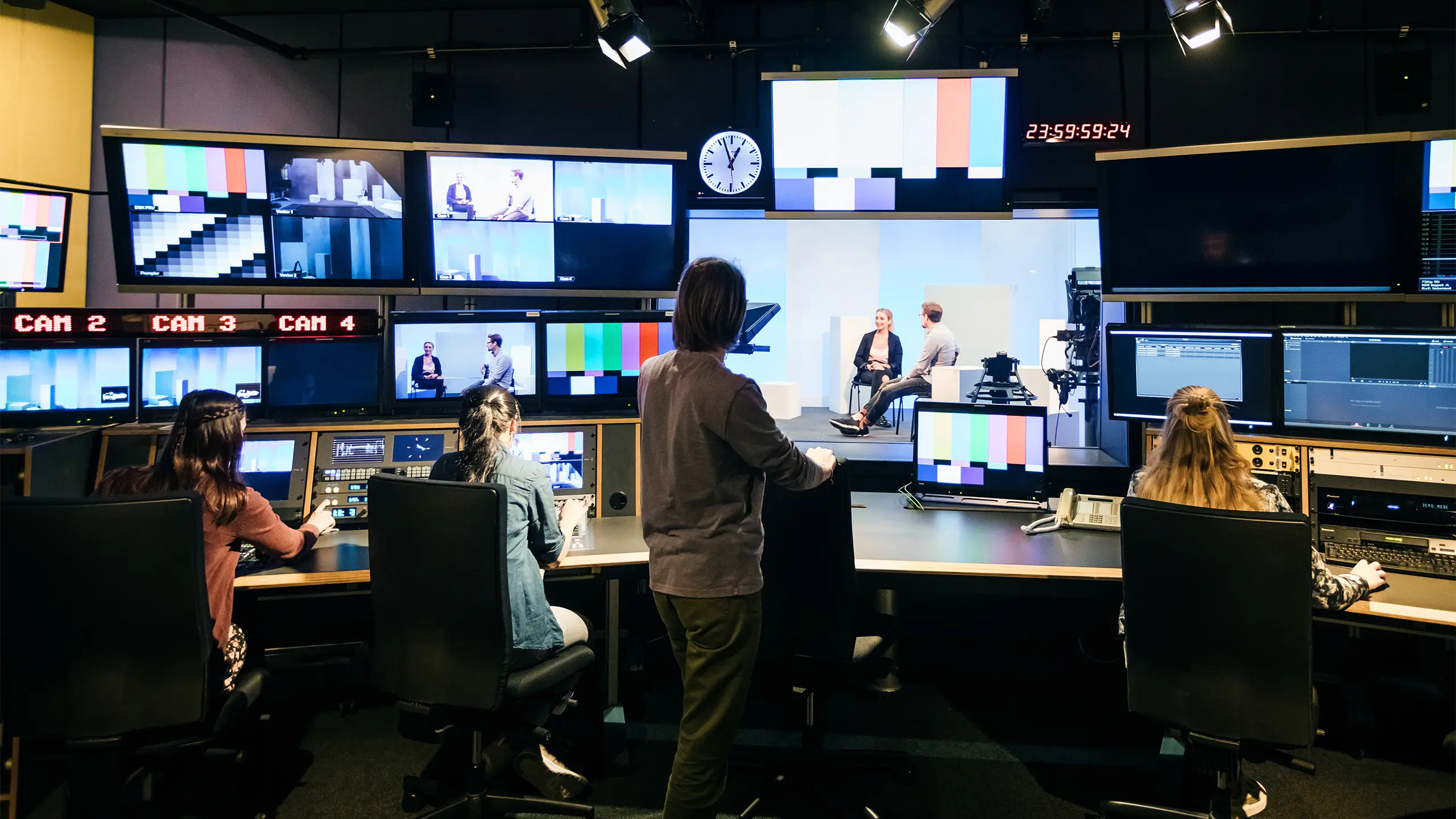 A group of university students working in a tv studio and learning how to use the equipment.