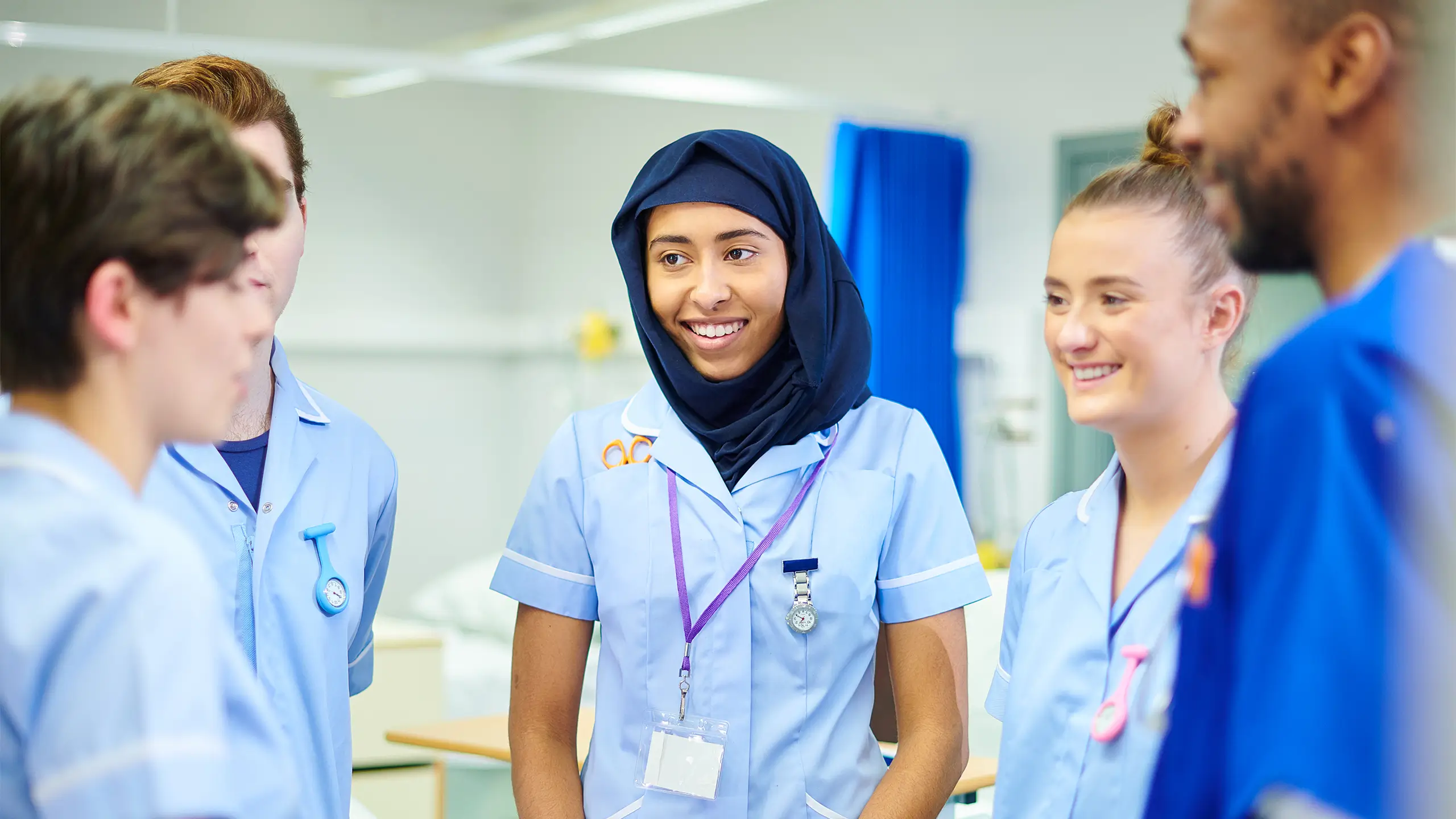 Four young medical students chat to each other and their manager after a shift on the wards