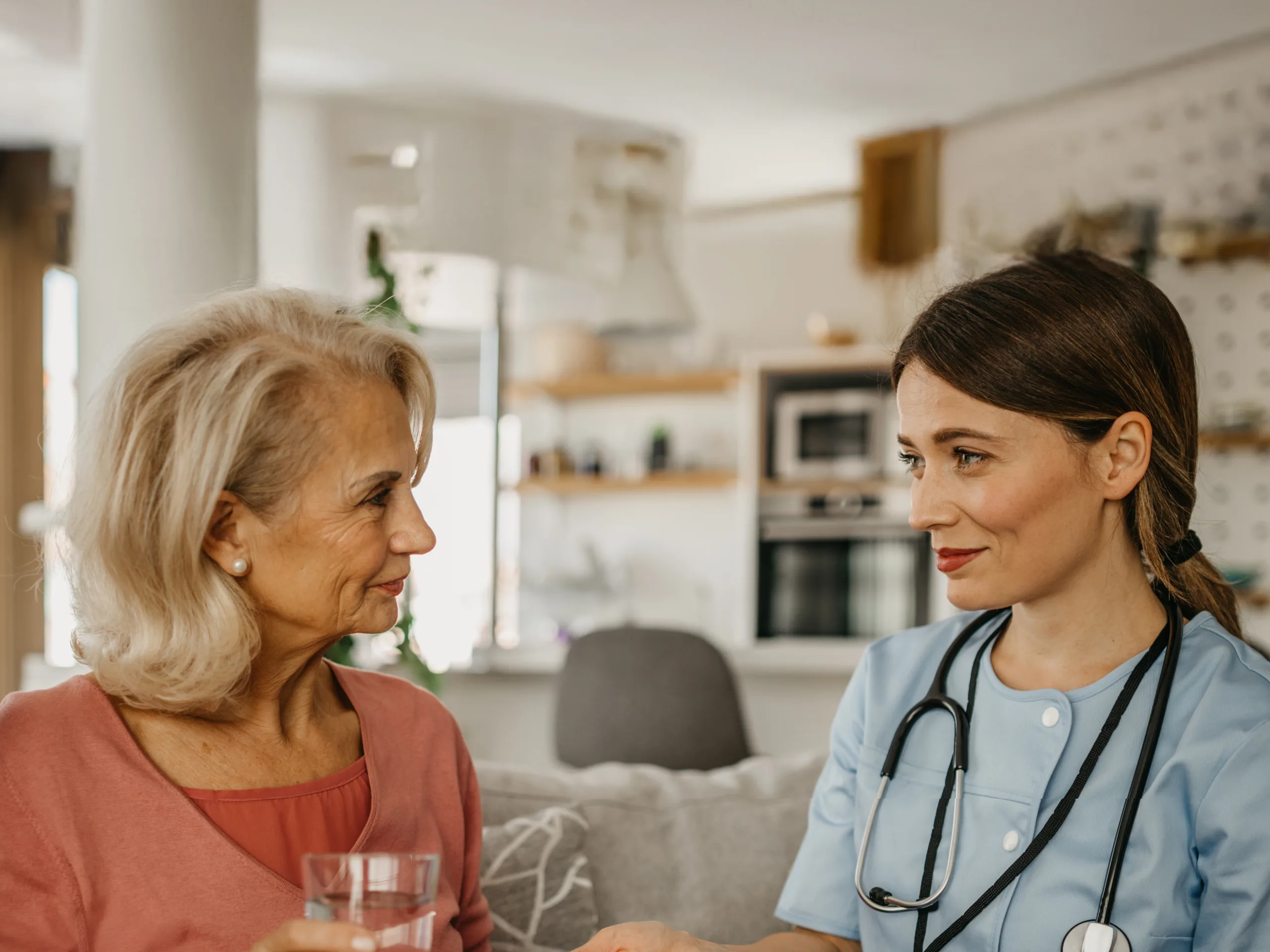 Shot of a nurse giving her patient pills. Smiling nurse in a home visit of the older couple, giving them pills to take.