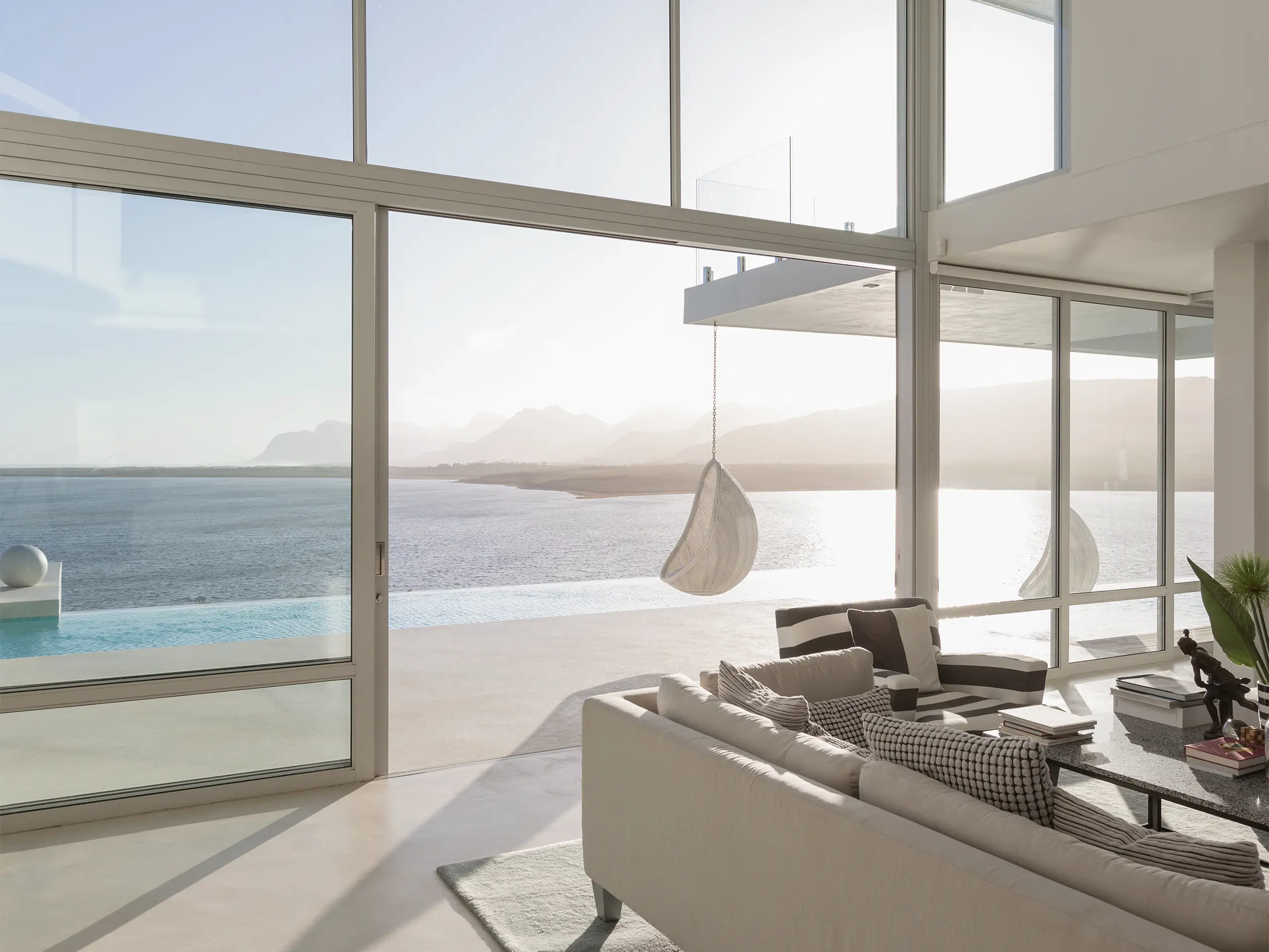 Sunny, tranquil modern luxury home showcase interior living room with ocean view