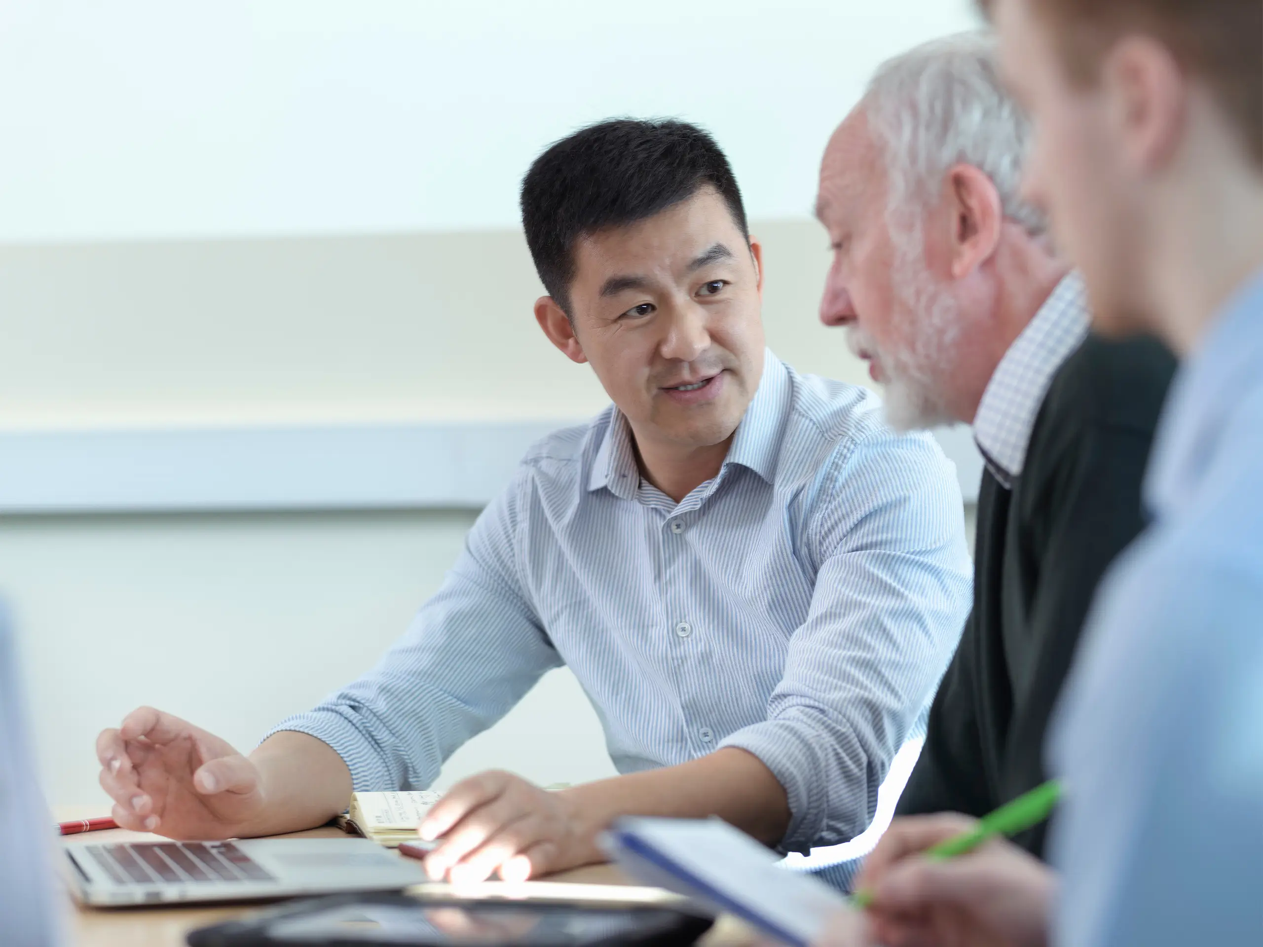 Younger and older scientists discussing pharmaceutical science project in meeting room